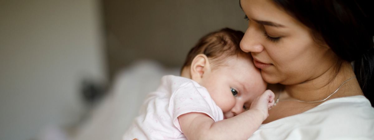 Mother holding her newborn baby at home